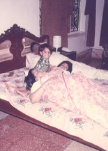 Vintage photo: Ajay Rungta (Dadu) and Ma (grandmother) in bed with grandchildren Chinu and Bhaiya, sharing a loving family moment.