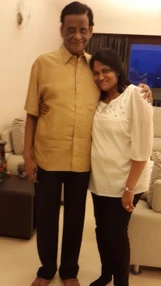 Ajay Rungta (Dadu) and Aarti standing together indoors. Dadu, in a gold shirt, has his arm around Aarti, in a white top.