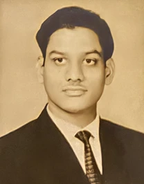 Formal portrait of a young Ajay 'Dadu' Rungta, looking thoughtful in a suit and tie. Sepia-toned image.
