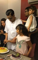 Ajay Rungta (Dadu) helps his granddaughter cut a birthday cake. Another granddaughter and family members are present.