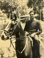 Sepia-toned old photograph of Ajay Rungta in his youth, wearing sunglasses and a sweater, sitting astride a horse.