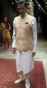 Ajay Rungta (Dadu) at 75, in traditional Indian attire: cream sadri, white kurta-churidar, red pocket square, smiling.