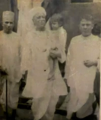 Vintage sepia photo: young Ajay Rungta (Dadu) as a child, held by one elder, with another elder standing beside them.