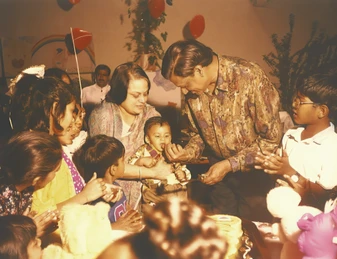 Ajay Rungta (Dadu) and Ma at grandson Aman's first birthday, Dadu affectionately offers cake to Aman amidst family.