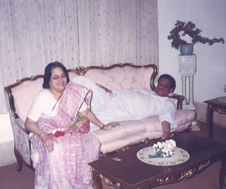 Ajay 'Dadu' Rungta lounging comfortably on a pink sofa, with a woman, likely his wife 'Ma', seated beside him smiling.