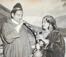 Vintage photo: Ajay Rungta (Dadu) and Ma in traditional attire. Ma offers a hookah to Dadu, who gazes at her.