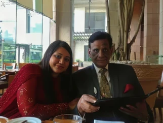 Ajay 'Dadu' Rungta, loving grandfather, with Tanya (likely granddaughter) at a restaurant. Dadu studies a menu; Tanya smiles.