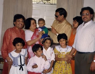 Ajay 'Dadu' Rungta in a gold shirt and sunglasses, pictured indoors with his loving family, including several young children.