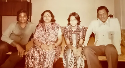 Vintage indoor photograph: Ajay Rungta (Dadu), Ma, Sanjeev, and Aarti are seated together on a sofa in a family portrait setting.