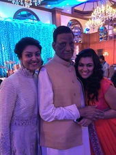 Ajay 'Dadu' Rungta smiling between Chinu and Popo. He wears a beige vest. They are at an indoor event with festive lighting.