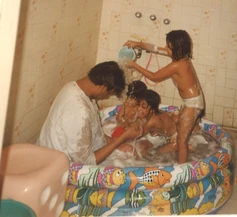 Dadu (Ajay Rungta), wet from play, joins his granddaughters in a soapy inflatable pool. One girl joyfully pours water.