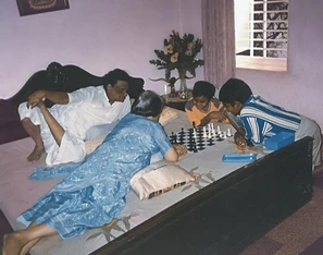 Ajay Rungta (Dadu), his wife (Ma), and two grandsons are engrossed in a game of chess on a bed. Dadu is in white, his wife in blue.