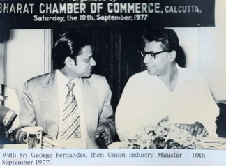 Black and white photo: Ajay Rungta (left, in suit) conversing with George Fernandes (right, in glasses) at a 1977 Calcutta event.