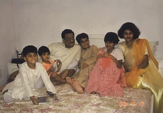 Ajay 'Dadu' Rungta sits on a bed with five grandchildren in festive attire, sharing a joyful moment during Diwali celebrations.