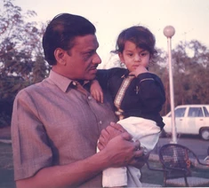Ajay Rungta (Dadu) in a collared shirt, lovingly holding his young grandson Bhaiya outdoors. Bhaiya looks towards the camera.