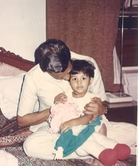 Vintage photo of Dadu (Ajay Rungta) affectionately kissing his grandchild Chinu, who is on his lap holding a doll.
