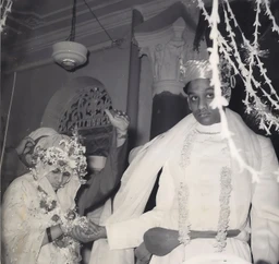 Black and white photo of Dadu and Ma in traditional attire during their wedding ceremony, holding hands.