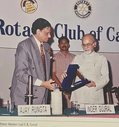 Ajay Rungta (Dadu) in a suit, receiving an award from former Indian Prime Minister I.K. Gujral at a Rotary Club event.