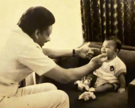 Sepia image: Ajay Rungta (Dadu) smiles, playing with baby Chinu on a couch. A tender moment between grandfather and grandchild.