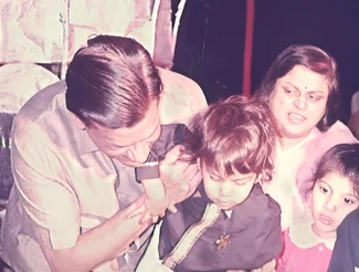 Ajay Rungta (Dadu) lovingly interacts with his young grandson Bhaiya at his first birthday celebration, with family nearby.
